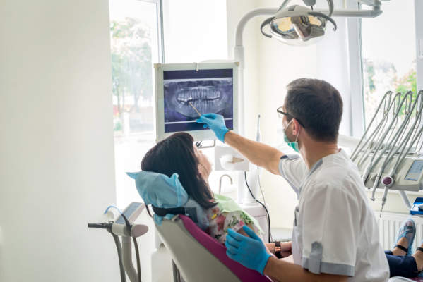 医生牙医显示在X射线患者的牙齿