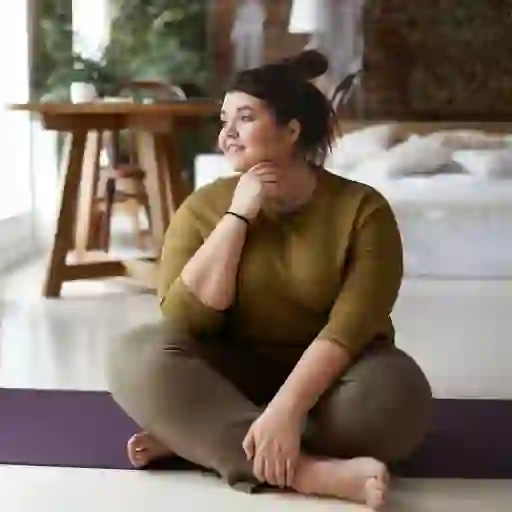 一位沉思的妇女坐在瑜伽垫上