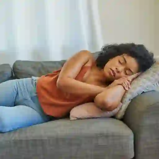 A tired woman naps on a couch