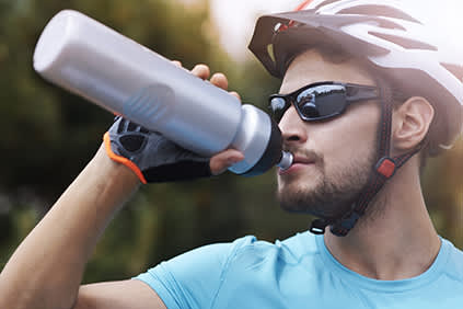 骑自行车的人用水瓶喝水。