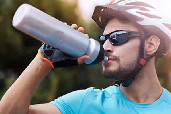 骑自行车的人用水瓶喝水。