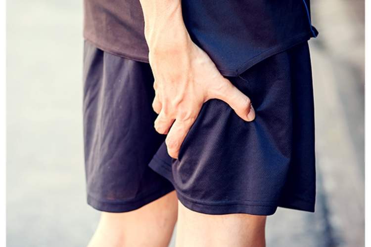 男子抓疼痛大腿的背部。