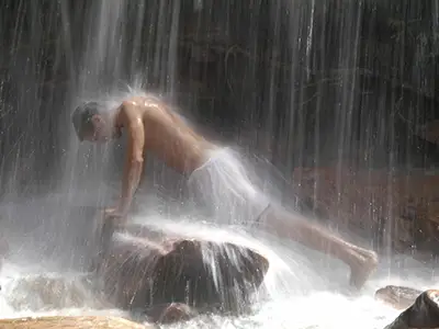 供以人员在瀑布下得到按摩在温泉。