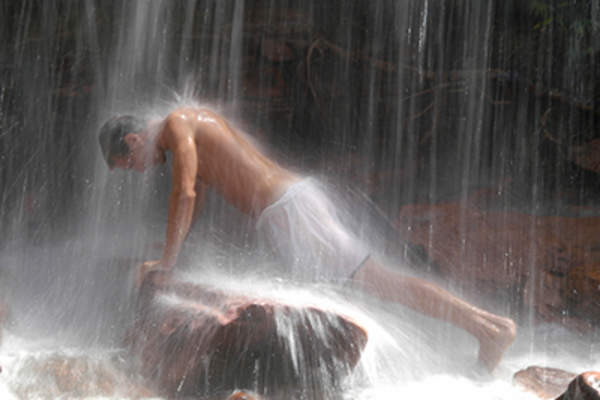 一个男人在水疗中心的瀑布下做按摩。