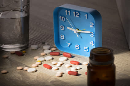 安眠药，闹钟，药瓶，并在床头柜上的一杯水。