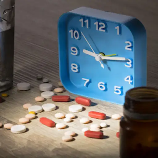 睡觉药片，闹钟，药瓶和杯水在床头柜。