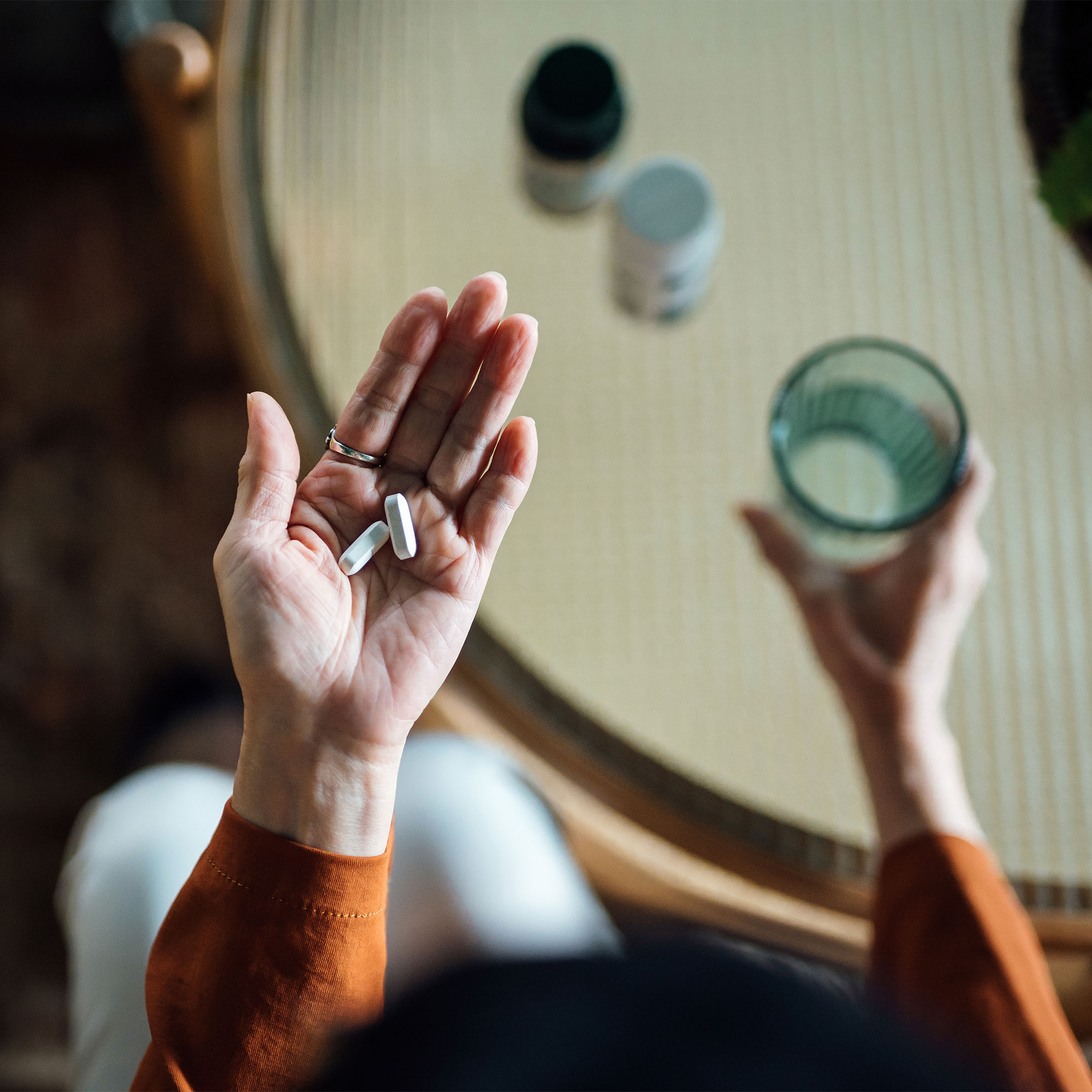 一个女人拿着两粒药丸和一杯水