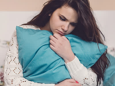 一个年轻的女人抱着枕头躺在床上。
