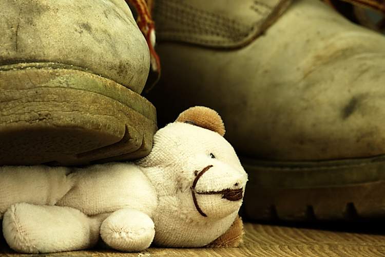 童年虐待,一只靴子踩在泰迪熊上。