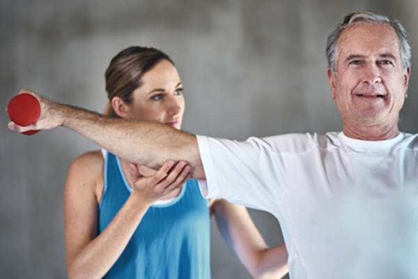 教练帮助这位老人与力量训练。