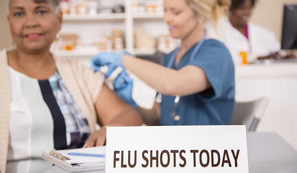 妇女在药房柜台注射流感疫苗。