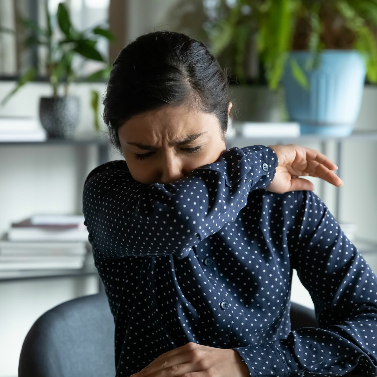 一个女人咳嗽到她的手肘