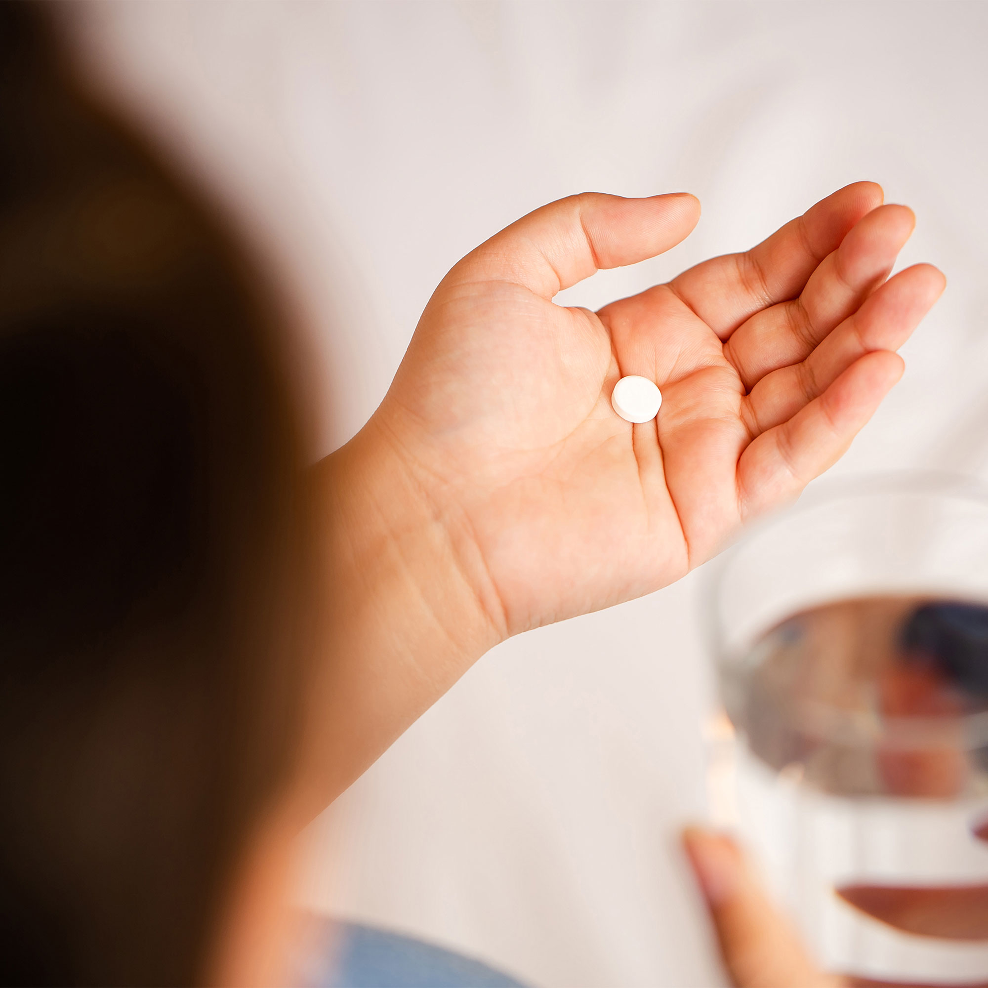 女人拿着一杯药和一杯水