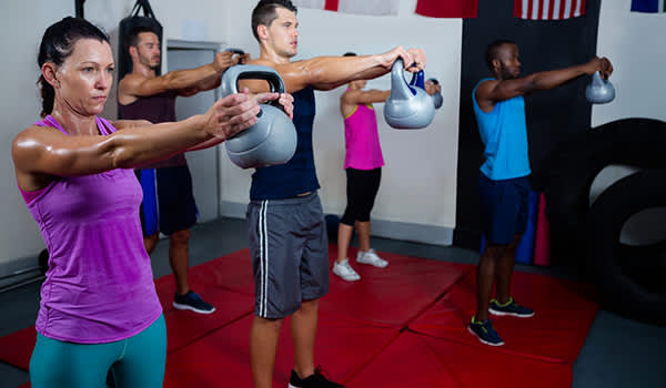 人们在健身房的形象中举起水壶的重量。