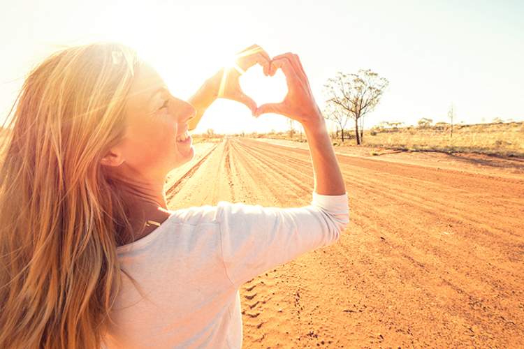 女人拿着心脏形手在沙漠中。