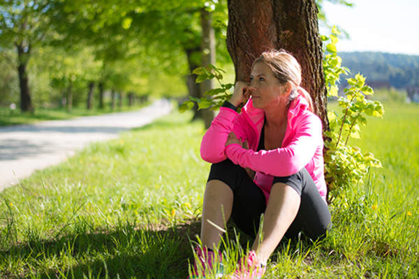 女人采取中止锻炼时间由靠在一棵树