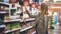 女子伸手在杂货店货架的食物。