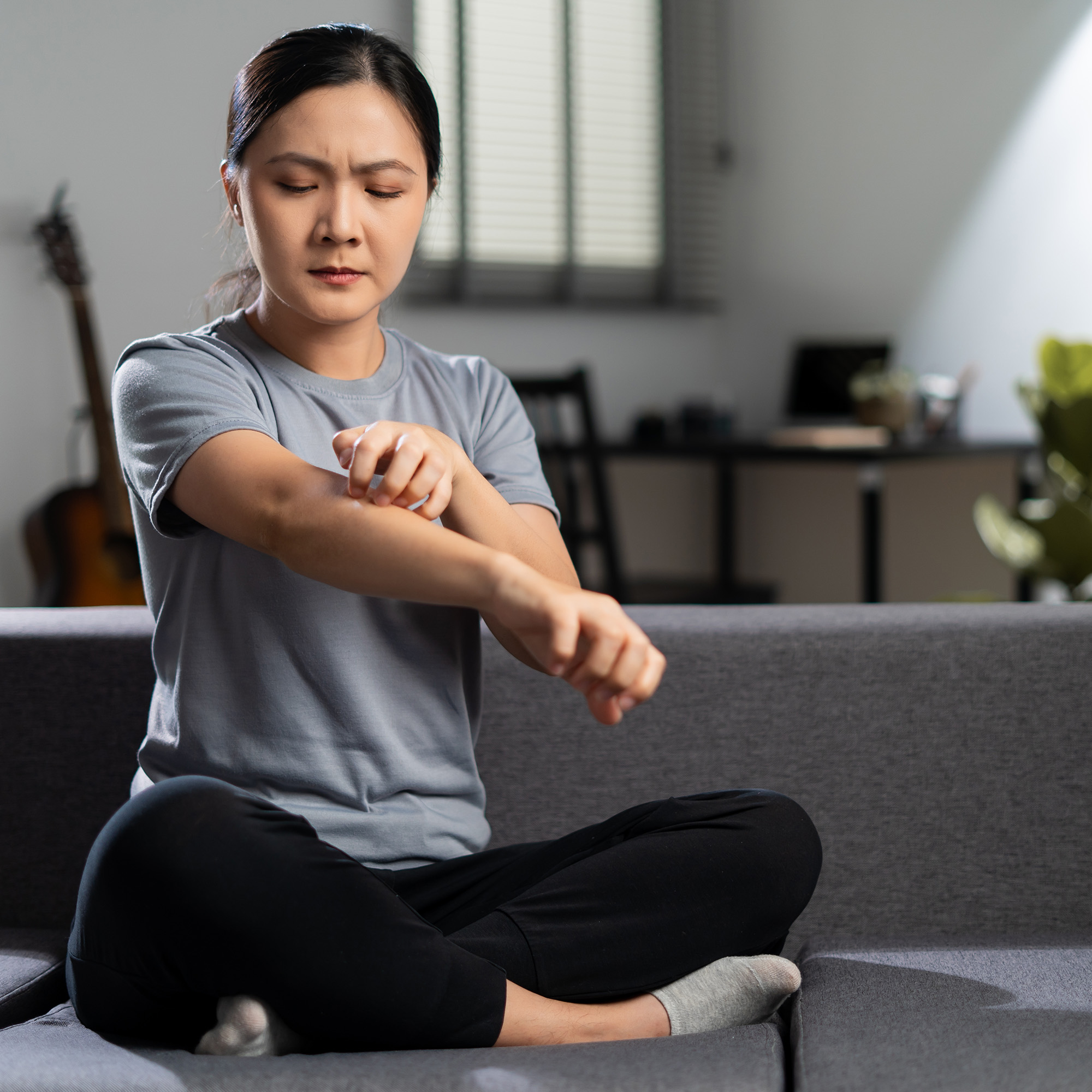 女人坐在家里客厅的沙发上挠皮肤
