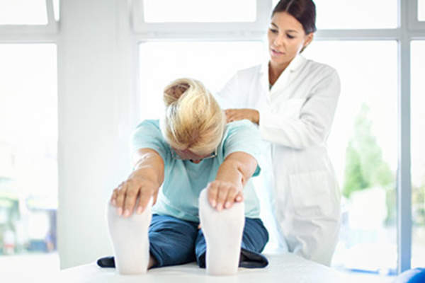 理疗师帮助一位年轻妇女伸展她疼痛的背部。