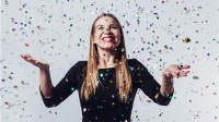 Happy young woman celebrating with confetti.