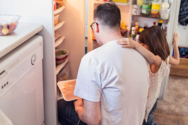 父亲抱着女儿从冰箱里拿食物。