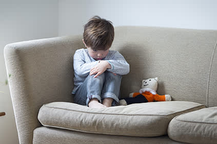 一个吓坏了的小男孩蜷缩在沙发上。
