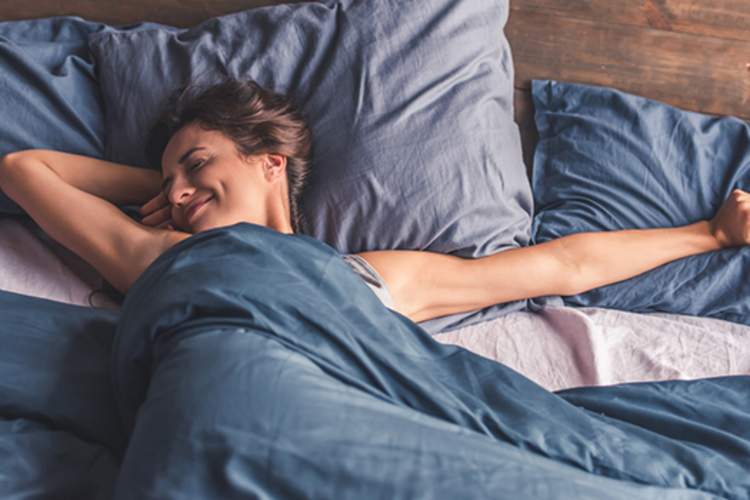 微笑的女人醒来精神焕发，躺在床上伸展。