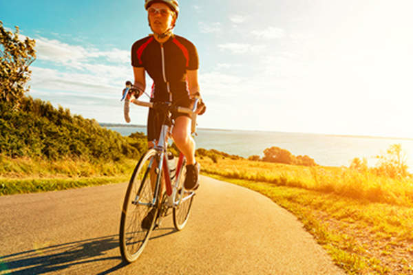 日落时分,女骑手骑着自行车爬上陡峭的山坡