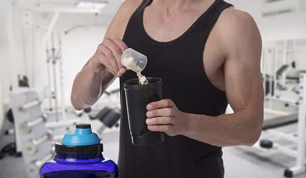 男子在健身房中加入蛋白粉。