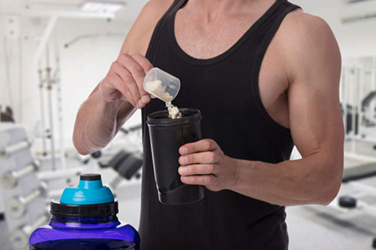 男子在健身房中加入蛋白粉。