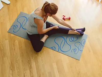 在瑜伽垫上使用阻力带的女人