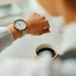 Person with coffee looking at watch