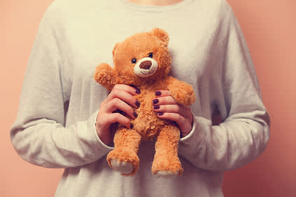 女人拥抱一个玩具熊舒适。