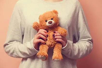 一个女人抱着一只泰迪熊安慰自己。