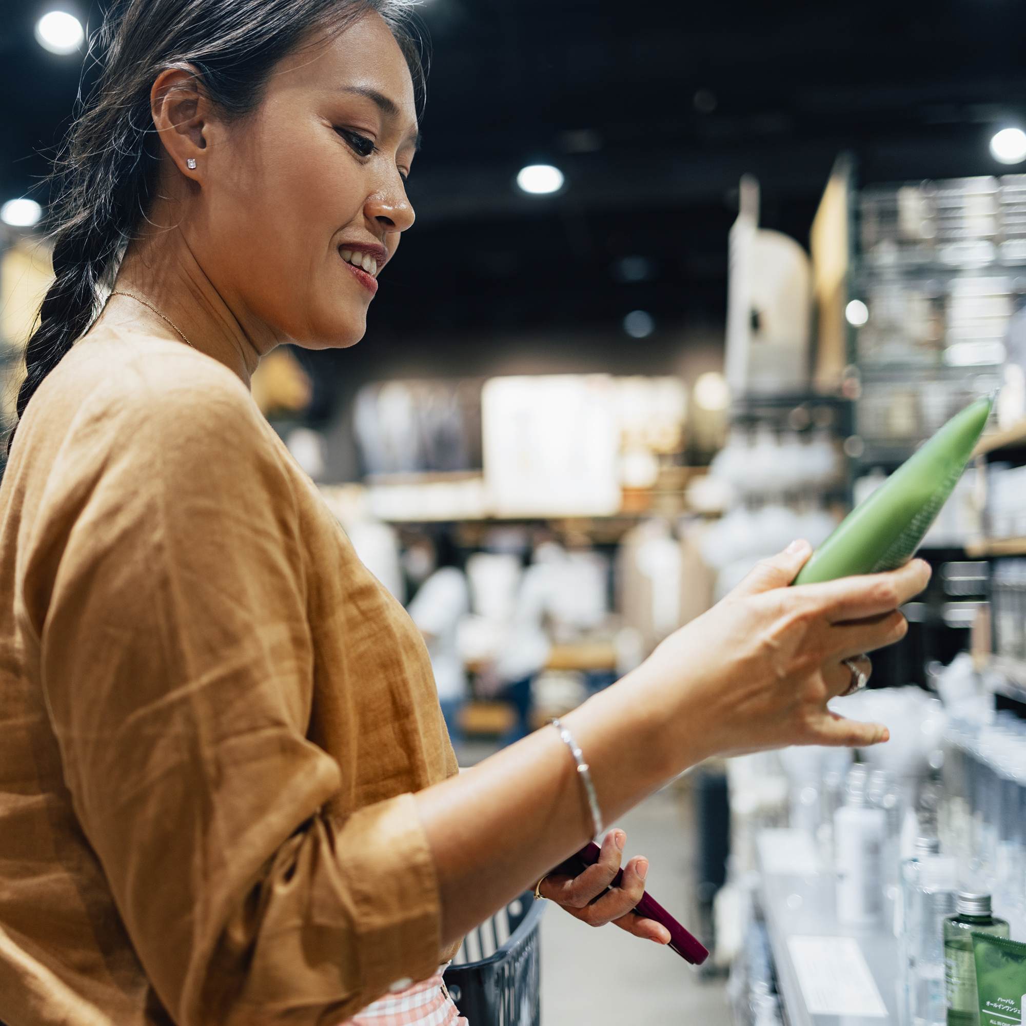 一名女子在商店里拿着一管化妆品，正在决定是否要买它