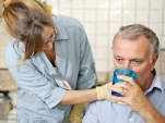 护士在男子喝水时检查他的喉咙。