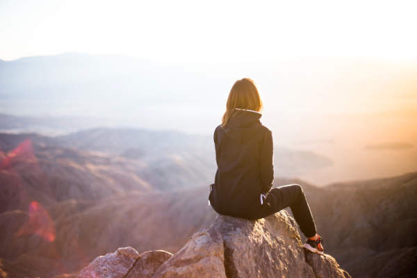 女子坐在山上看日落