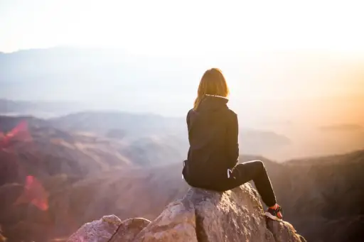 女人坐在山上看日落