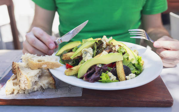 健康的午餐 - 人吃沙拉与鳄梨