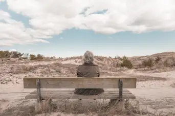 senior sitting alone near beach during winter
