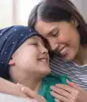 拥抱她的儿子的微笑的母亲被争夺白血病。