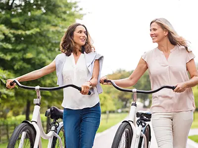 微笑的妇女朋友走自行车。