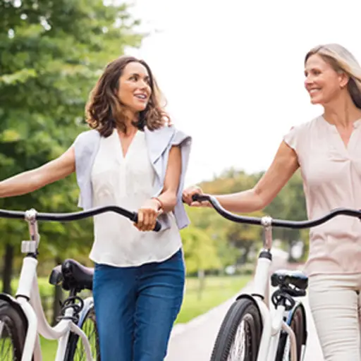 微笑的女性朋友步行自行车。