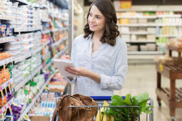 女人拿着单子在杂货店买东西。