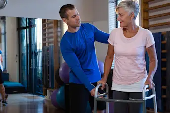 Woman working with physical therapist using a walker.