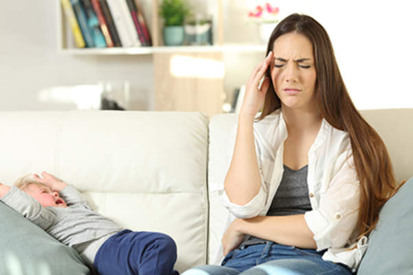 母亲坐在沙发上痛苦地看着孩子哭泣。