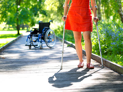 一名妇女拄着拐杖，背景是轮椅。