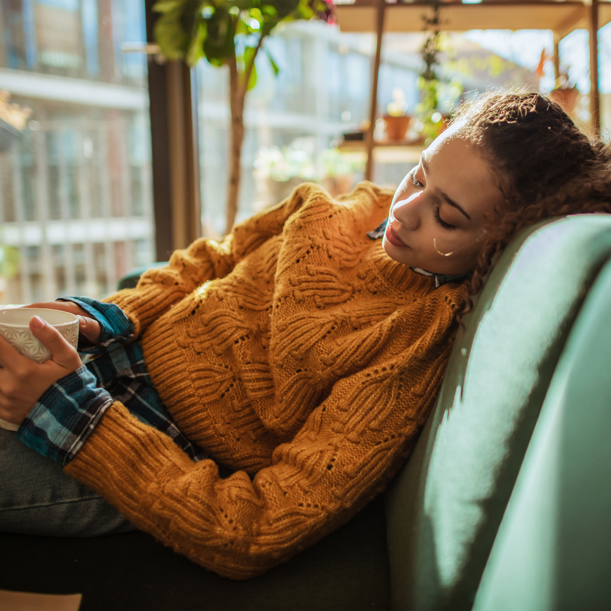 一个女人拿着杯子躺在沙发上