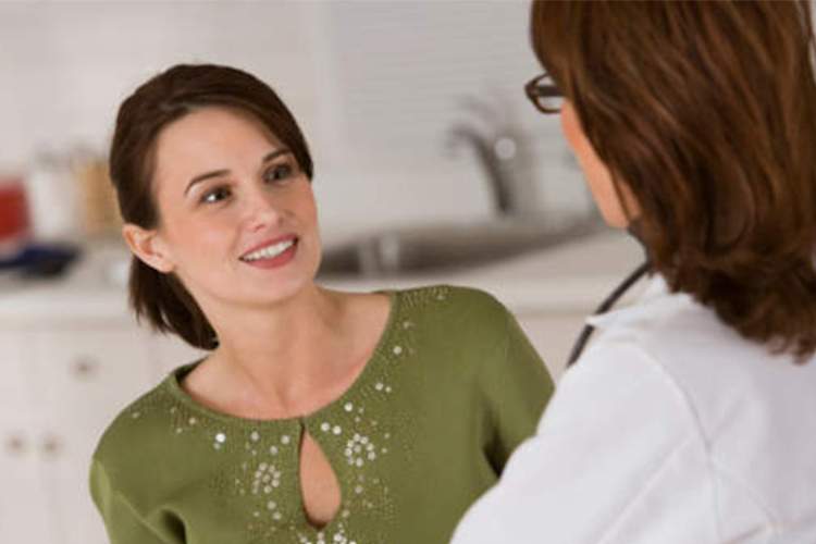 年轻的女人微笑着和她的医生交谈。