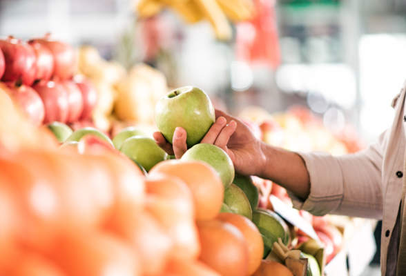 在农贸市场，一个女人伸手去拿苹果